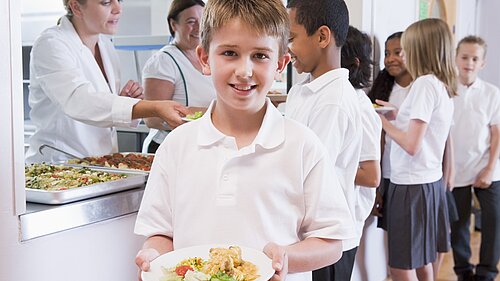 A boy holding a plate of food after leaving the dinner line.